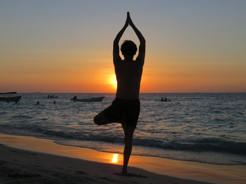 arafed man doing yoga on the beach at sunset