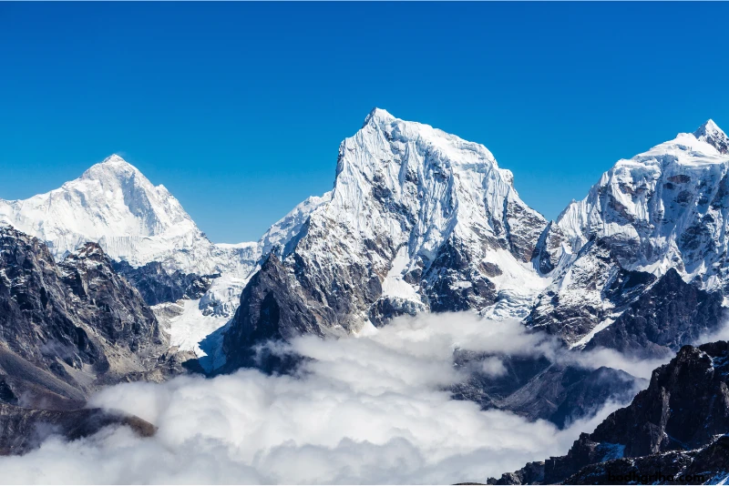 mountains covered in snow and clouds with a person standing