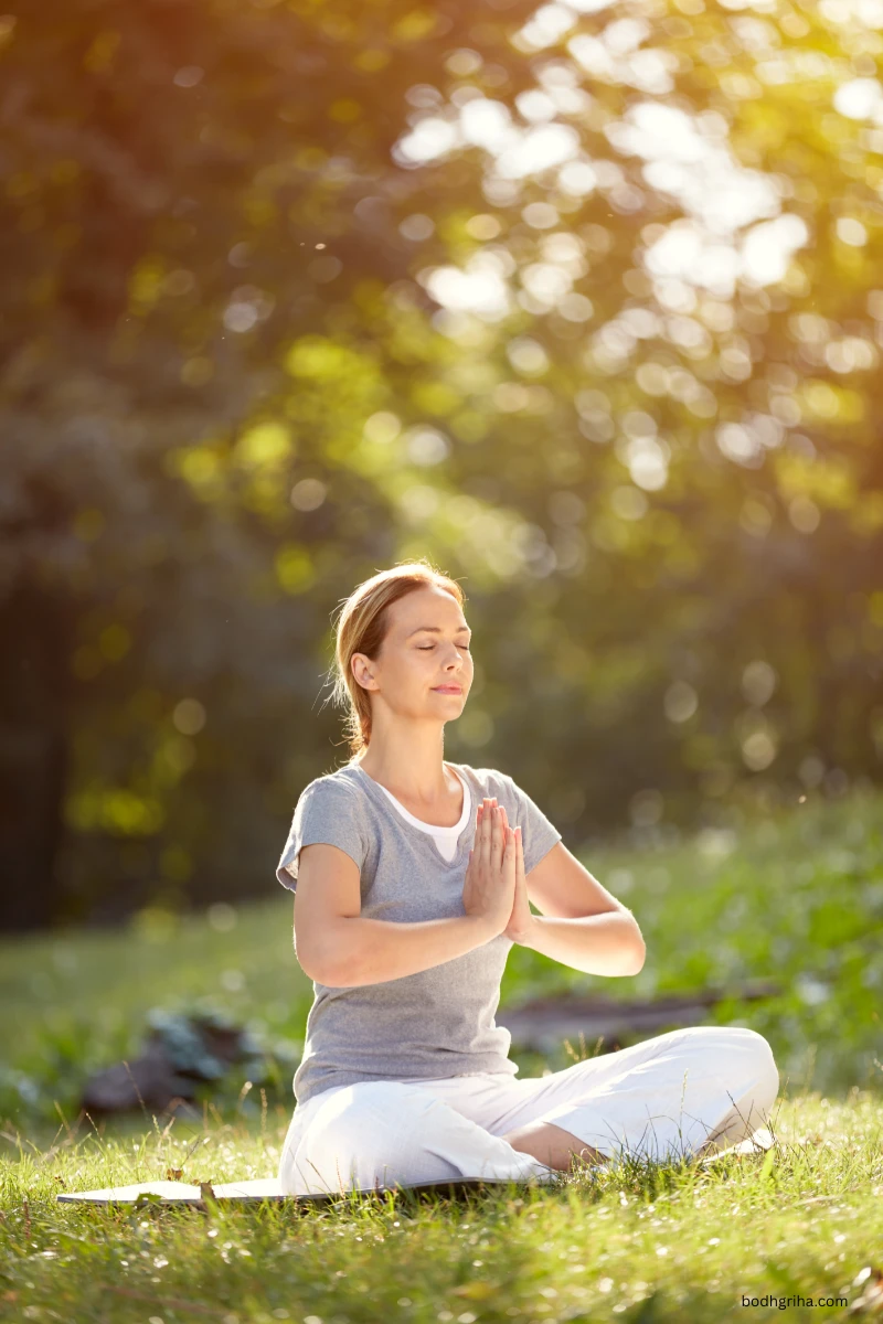 woman sitting in a yoga pose in the grass with